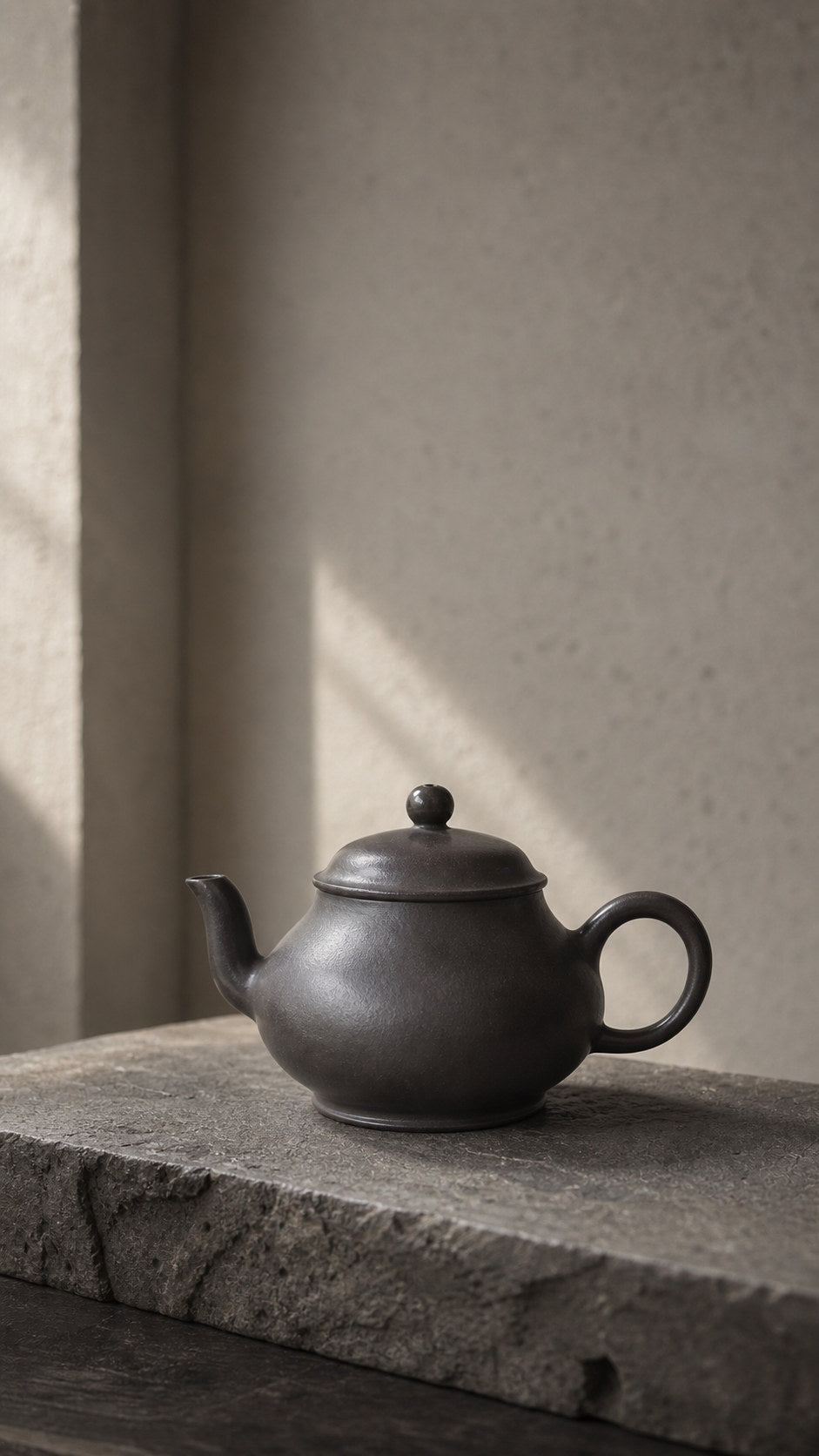 Hei Duntou Pan Hu teapot, full side view on gray stone
