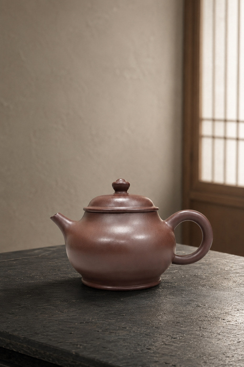 Pan Hu teapot, wide side view on a dark tabletop in soft window light