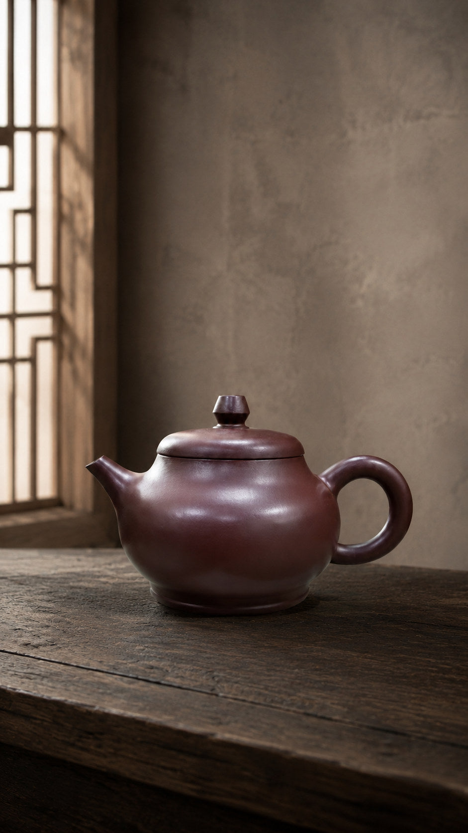 Pan Hu teapot, wide side view on a dark table beside a lattice window