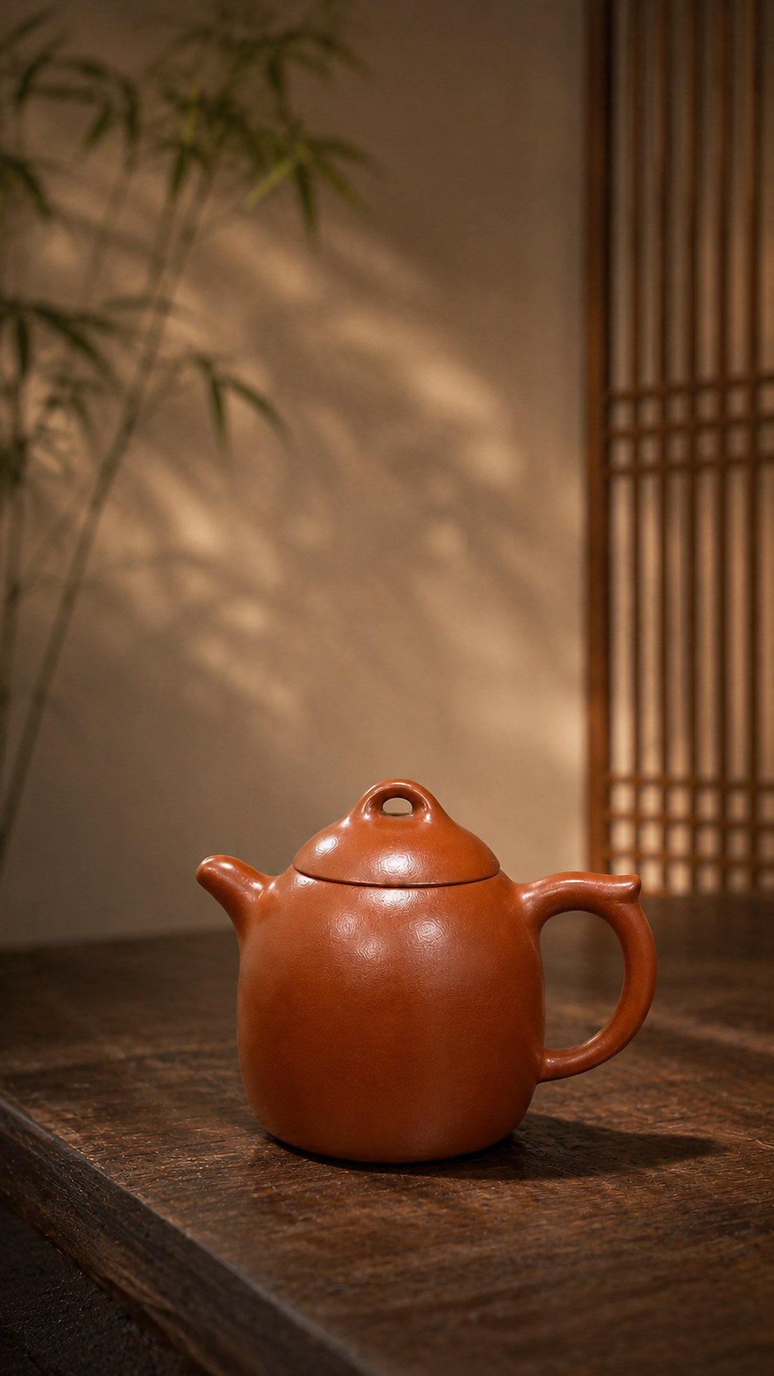 Red Jiangponi Qinquan teapot in warm bamboo-filtered light