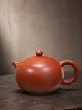 Xishi teapot in Dahongpao Clay, full side view of the rounded body and circular handle